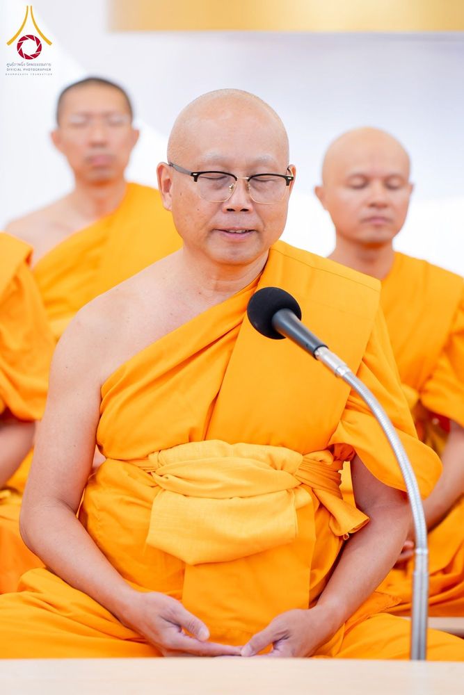 พระภิกษุสงฆ์สวมจีวรสีเหลืองทองกำลังกล่าวสวดมนต์ผ่านไมโครโฟนในพิธีทางศาสนา