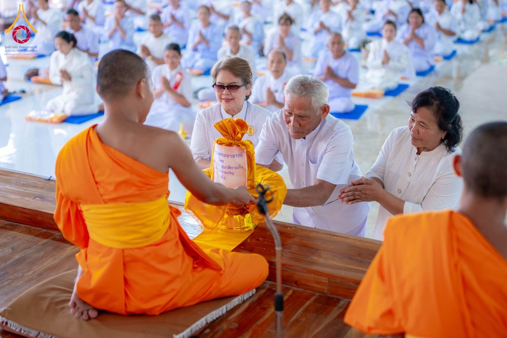 กลุ่มพุทธศาสนิกชนในชุดขาวกำลังถวายสังฆทานแด่พระภิกษุสงฆ์ในงานอบรมธรรมะ
