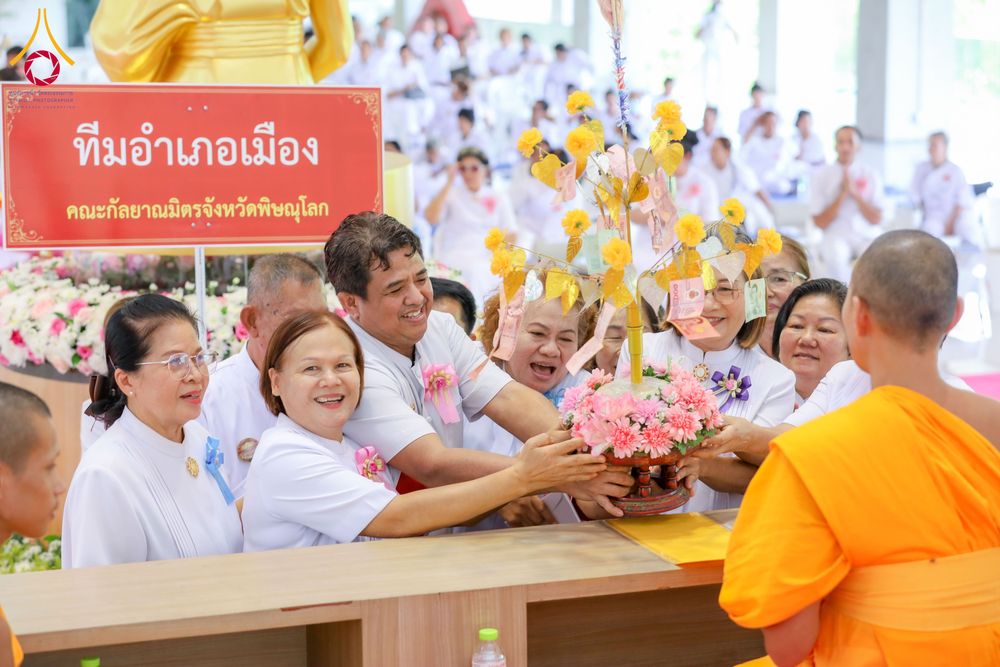 กลุ่มอุบาสกอุบาสิกาในชุดขาวกำลังประคองพุ่มกฐินถวายแด่พระภิกษุสงฆ์