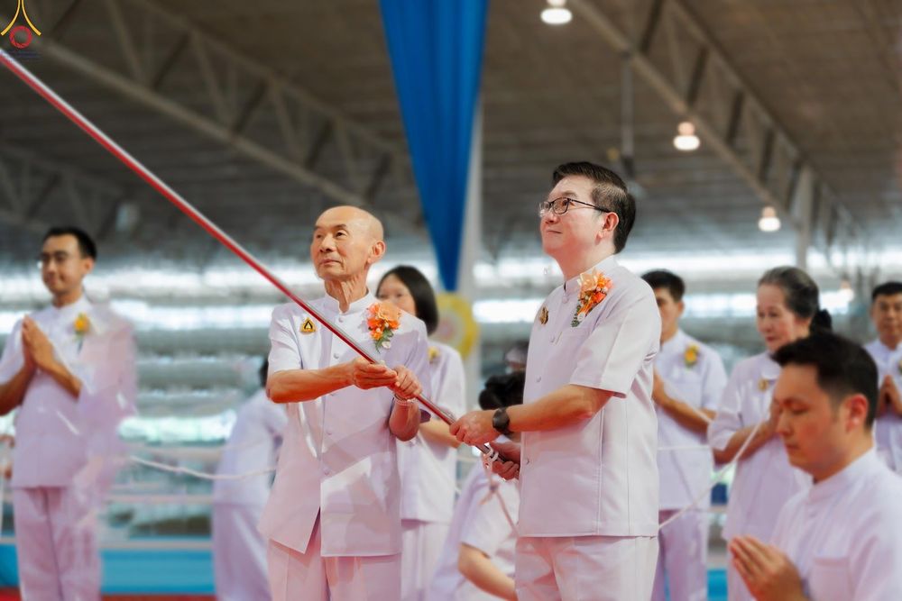 กลุ่มคนในชุดสีขาวกำลังร่วมพิธีจุดเทียนใจ ไฟนิรันดร์ อนันตชัย ภายในอาคาร