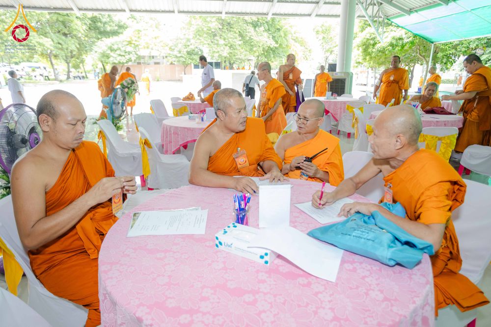 พระภิกษุสงฆ์หลายรูปกำลังนั่งประชุมและจดบันทึกเอกสารร่วมกันรอบโต๊ะกลมในงานสัมมนา