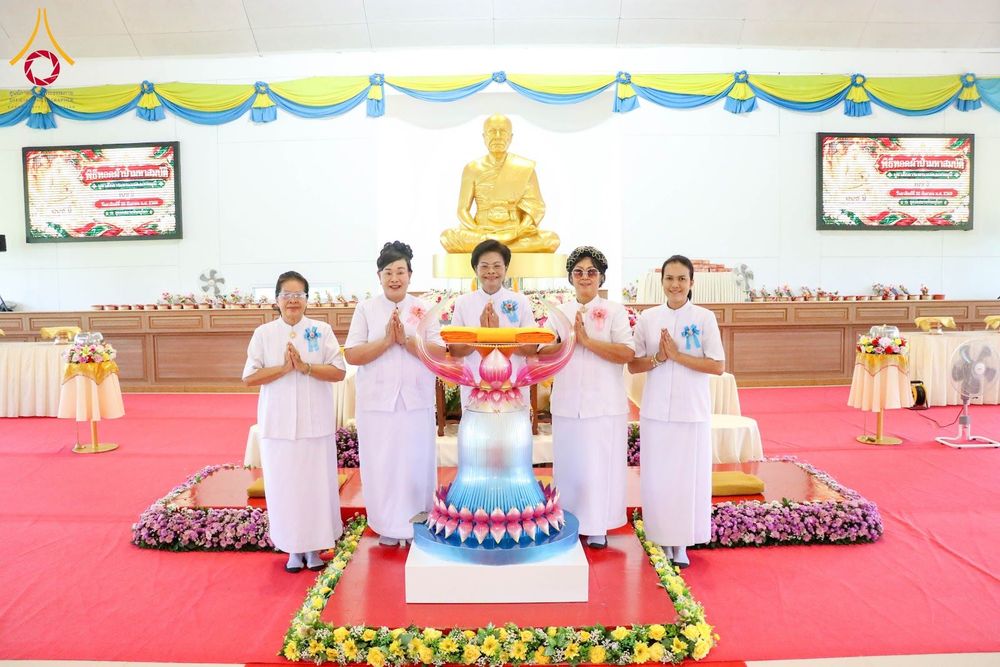 อุบาสิกาแก้ว 5 ท่านยืนพนมมือหน้าพานพุ่มดอกบัวจำลองและรูปปั้นสีทองภายในอาคาร