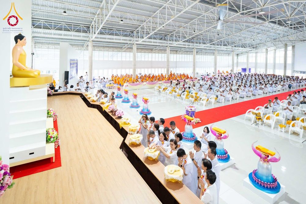 พุทธศาสนิกชนสวมชุดขาวร่วมพิธีทางศาสนาภายในอาคารขนาดใหญ่ที่มีพระพุทธรูปประดิษฐานอยู่ด้านหน้า