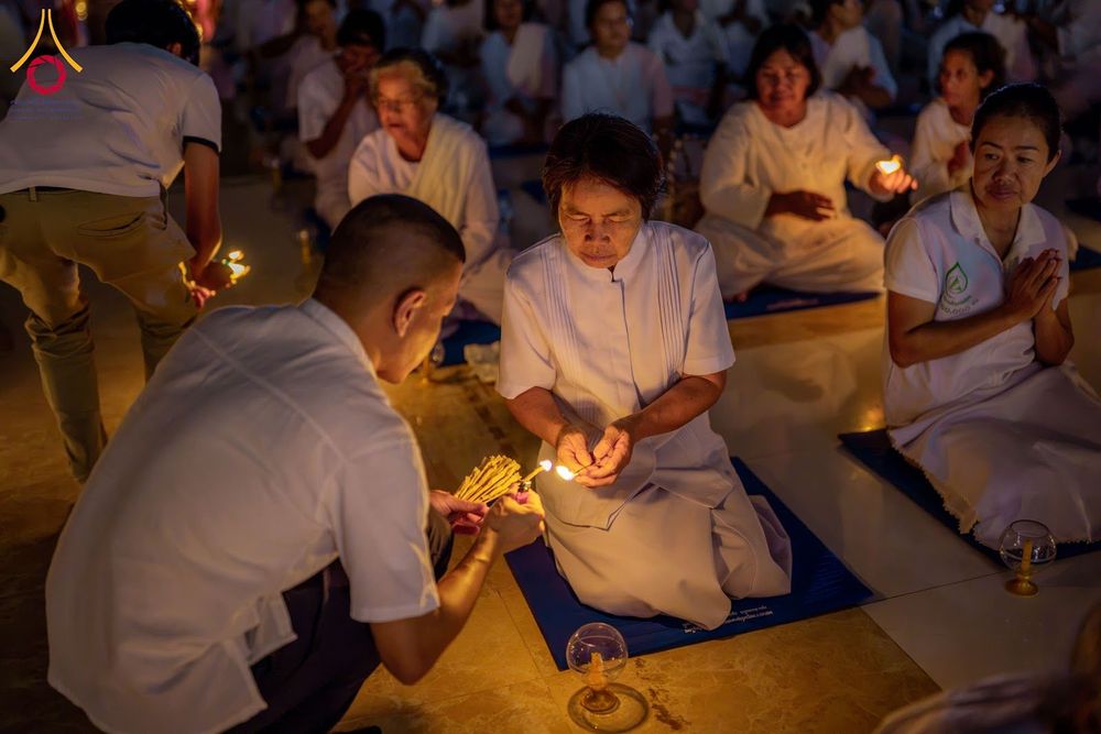 กลุ่มคนสวมชุดสีขาวกำลังจุดเทียนในกิจกรรมอบรมทางศาสนา