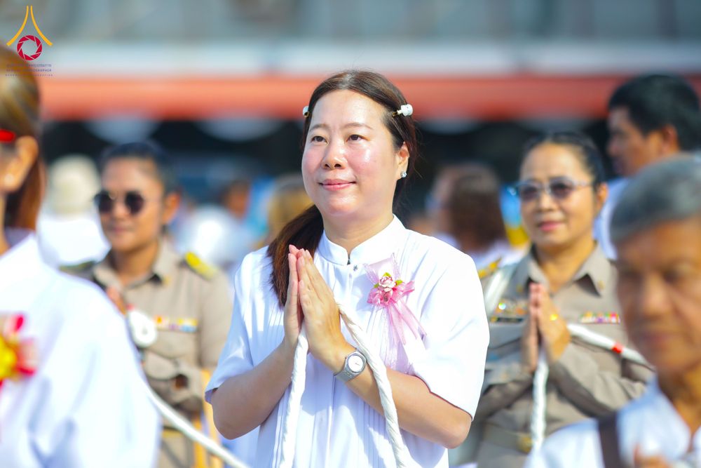 หญิงไทยสวมชุดขาวประนมมือไหว้ในพิธีทางศาสนา ท่ามกลางผู้เข้าร่วมพิธีคนอื่นๆ