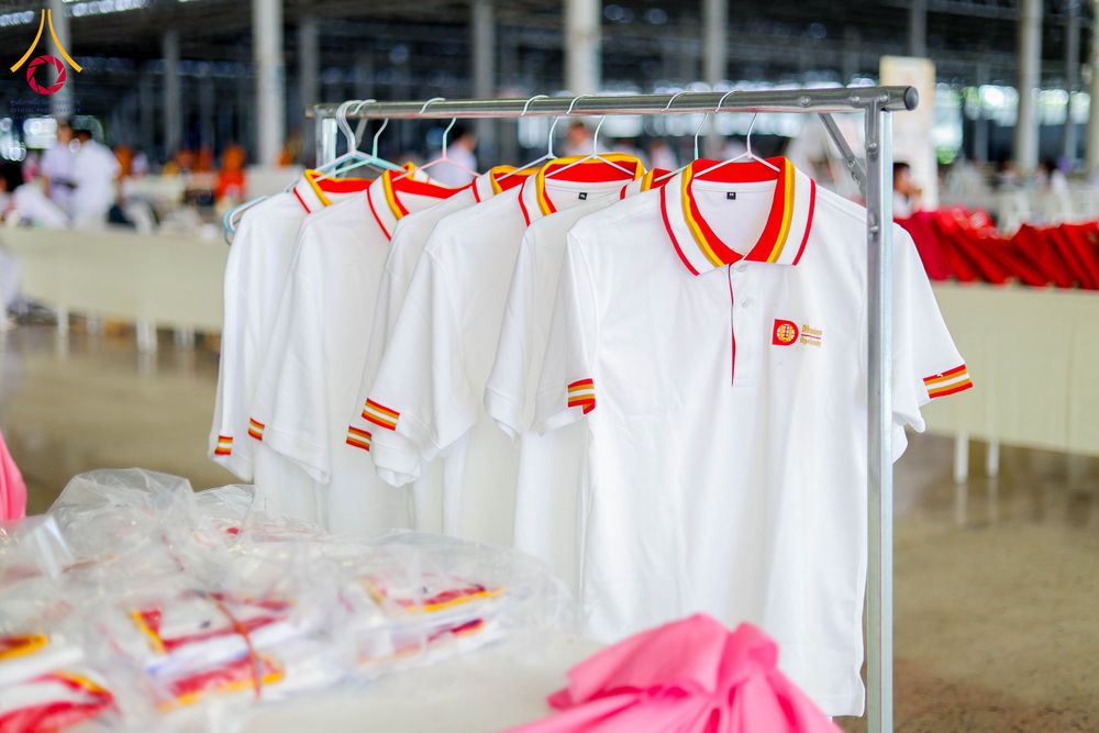 เสื้อโปโลสีขาวคอปกสีแดงเหลืองแขวนบนราวเหล็กภายในอาคาร