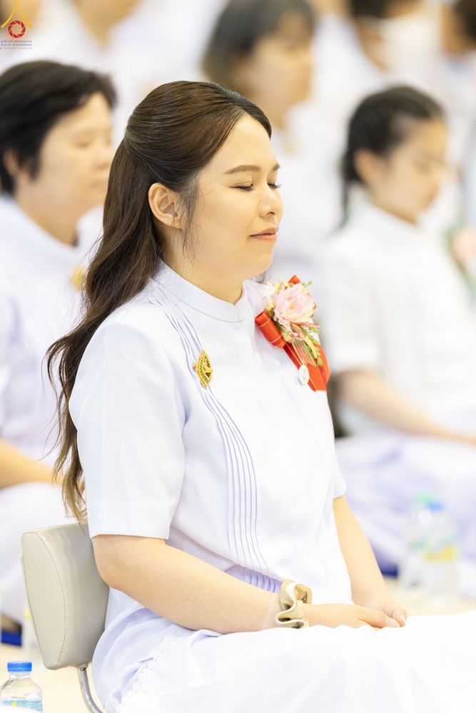 หญิงสาวสวมชุดขาวนั่งหลับตาทำสมาธิในพิธีทางศาสนา