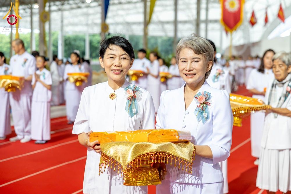 หญิงไทยสองท่านสวมชุดสีขาวถือพานผ้าไตรจีวรในพิธีทางศาสนา