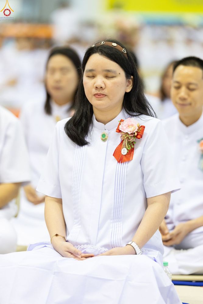 หญิงสาวสวมชุดขาวนั่งหลับตาทำสมาธิในพิธีทางศาสนา