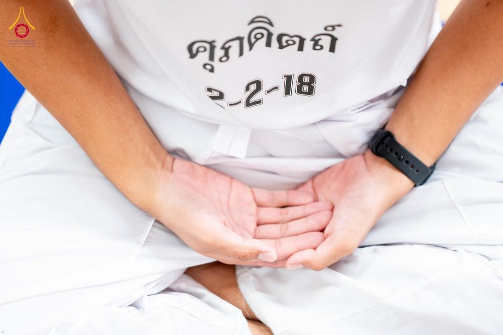 นักเรียนนายสิบตำรวจสวมชุดสีขาวกำลังนั่งสมาธิโดยวางมือประสานกันบนตัก