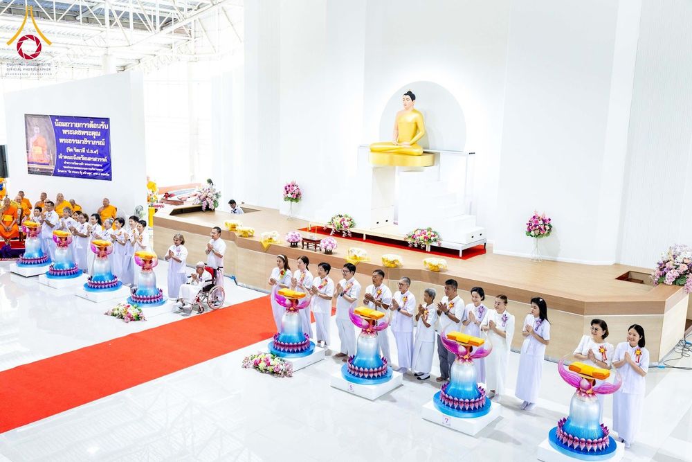 กลุ่มพุทธศาสนิกชนในชุดขาวกำลังประกอบพิธีทางศาสนาหน้าพระพุทธรูปองค์ประธานภายในอาคาร