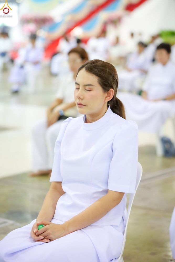 หญิงสาวสวมชุดสีขาวนั่งหลับตาทำสมาธิในอาคารปฏิบัติธรรม