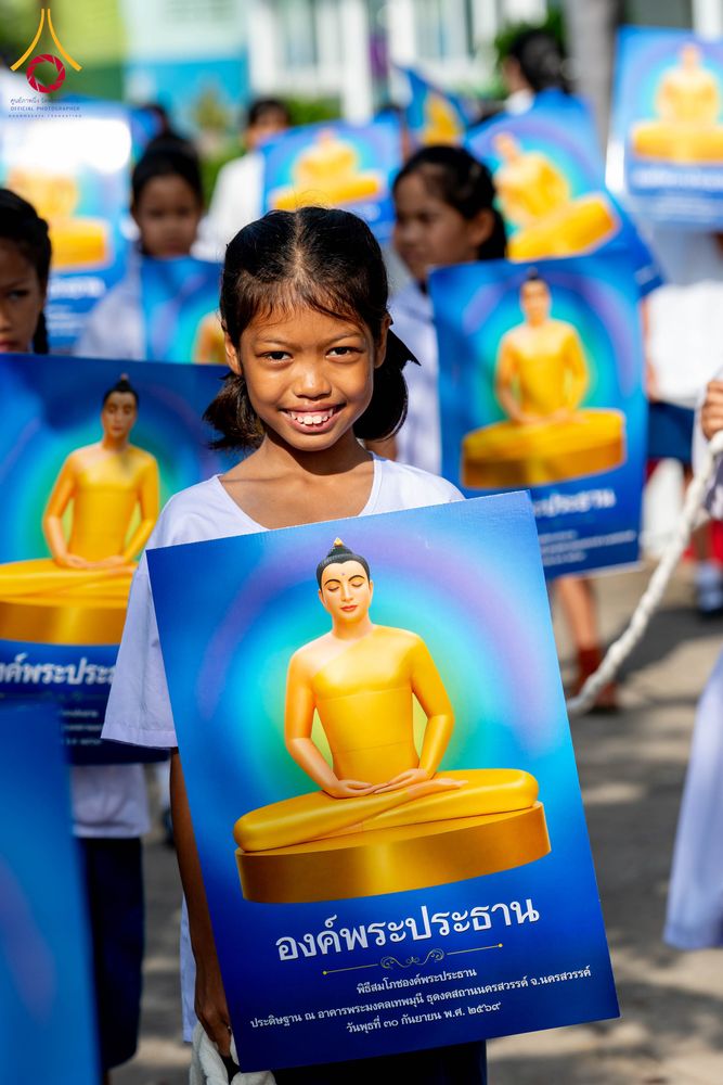 เด็กหญิงถือป้ายภาพพระพุทธรูปสีทองในกิจกรรมทางศาสนา