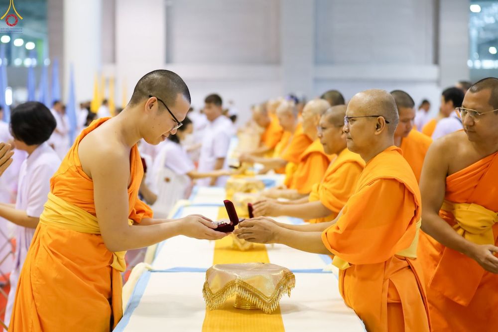 พระภิกษุสงฆ์ในจีวรสีส้มกำลังส่งมอบกล่องพระของขวัญให้แก่กันในพิธีทางศาสนา