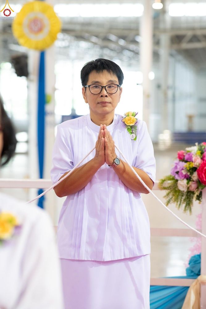 หญิงไทยสวมชุดสีขาวพนมมือถือสายสิญจน์ในพิธีทางศาสนา