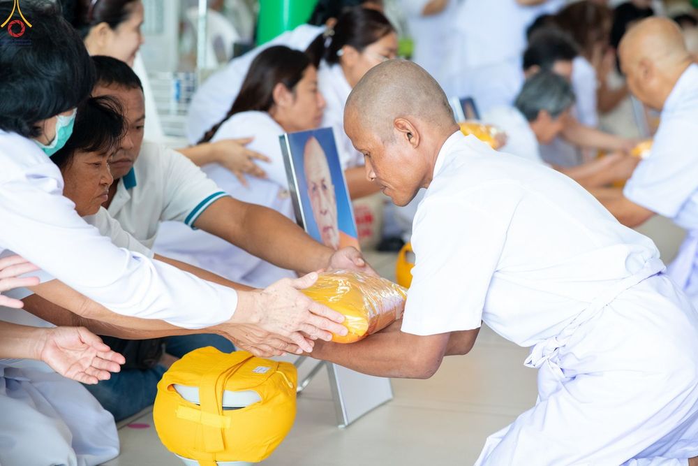 นาคในชุดขาวกำลังรับผ้าไตรจากญาติโยมในพิธีอุปสมบท