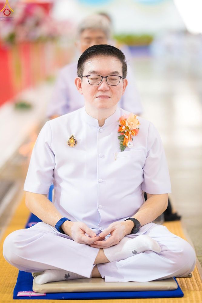 ชายสวมชุดขาวนั่งหลับตาสมาธิบนเบาะรองนั่ง