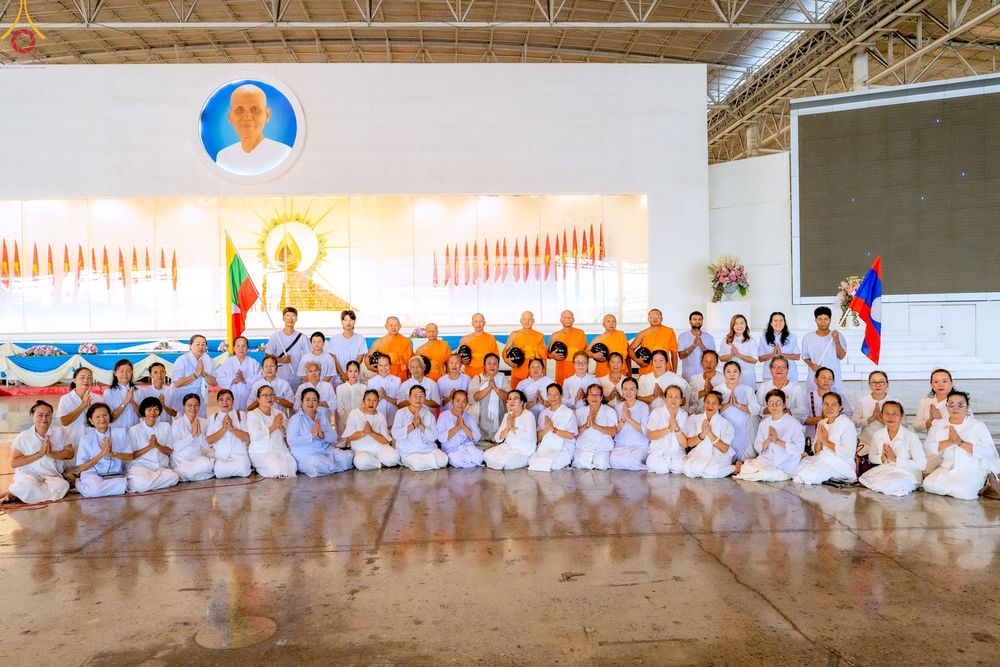 กลุ่มพระภิกษุและพุทธศาสนิกชนชุดขาวถ่ายภาพร่วมกันภายในอาคารสภาธรรมกายสากล