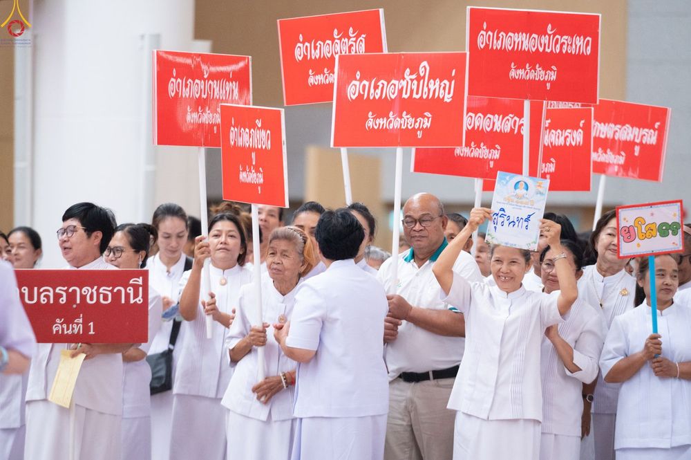 กลุ่มคนสวมชุดขาวถือป้ายชื่ออำเภอและจังหวัดในภาคอีสานเพื่อเข้าร่วมงานสัมมนา