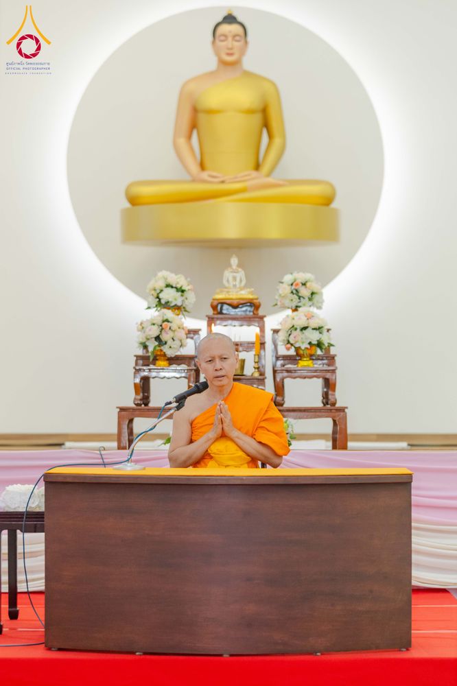 พระภิกษุสงฆ์กำลังประนมมือบรรยายธรรมหน้าพระพุทธรูปสีทอง