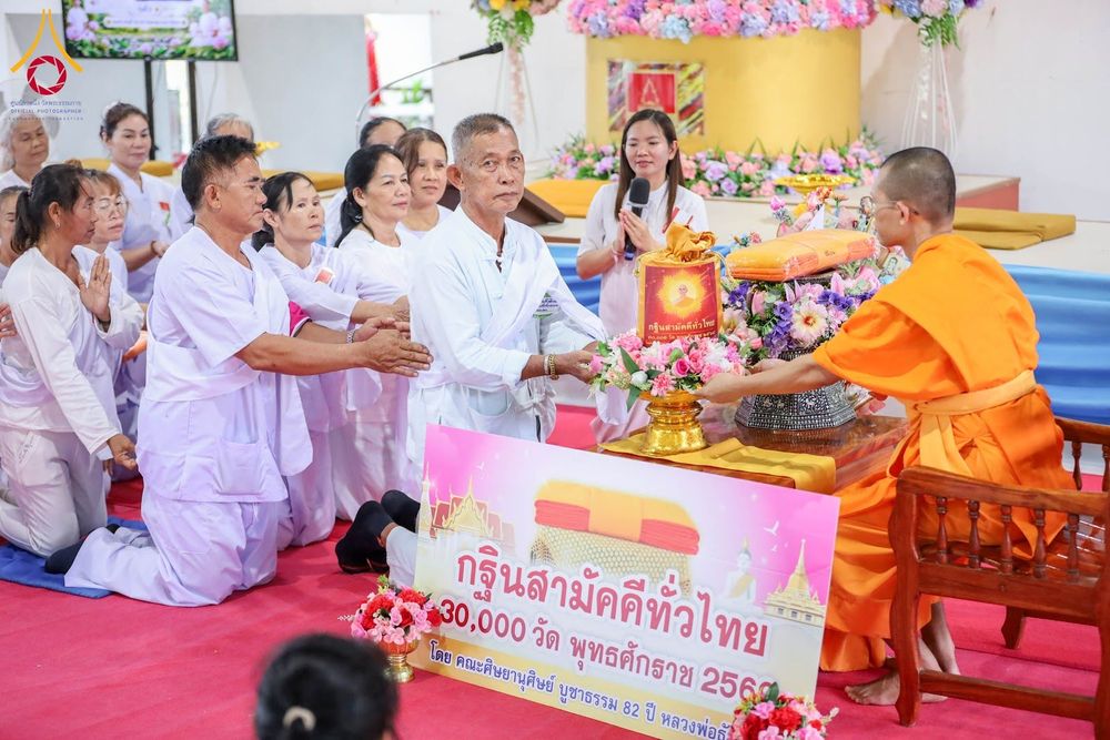 กลุ่มอุบาสกและอุบาสิกาในชุดขาวกำลังประเคนผ้ากฐินแด่พระภิกษุสงฆ์ในพิธีทางศาสนา