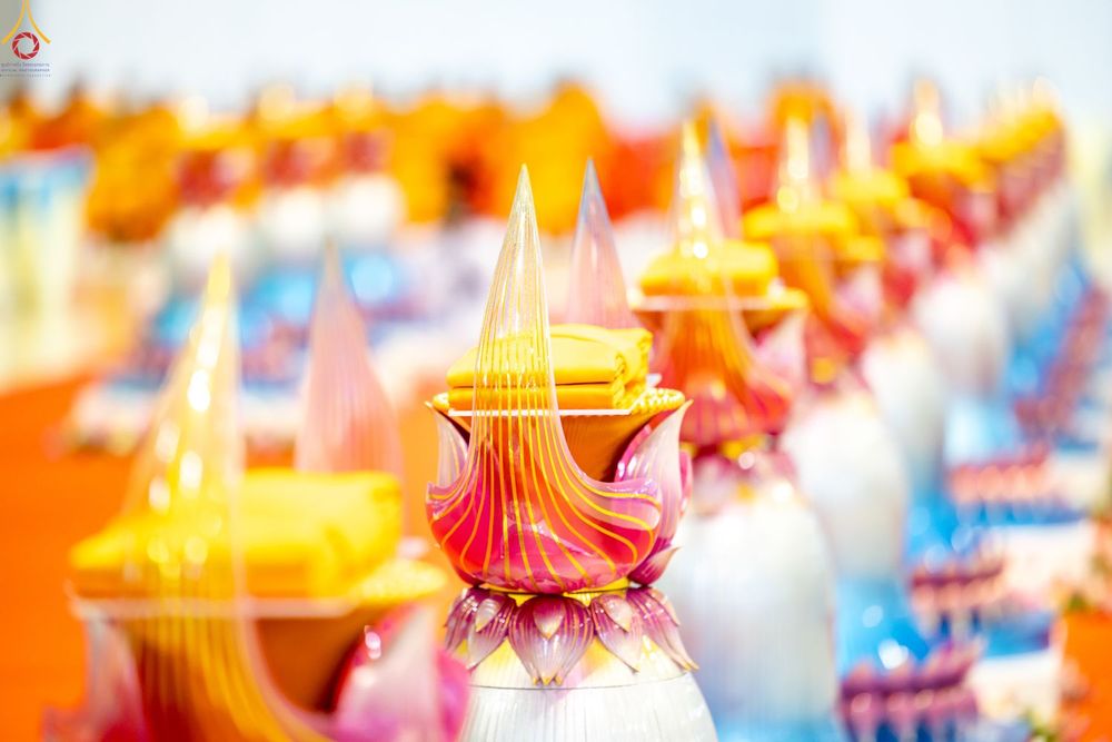 พานพุ่มสีชมพูทองวางเรียงรายพร้อมผ้าไตรสีเหลืองทองในพิธีทางศาสนา