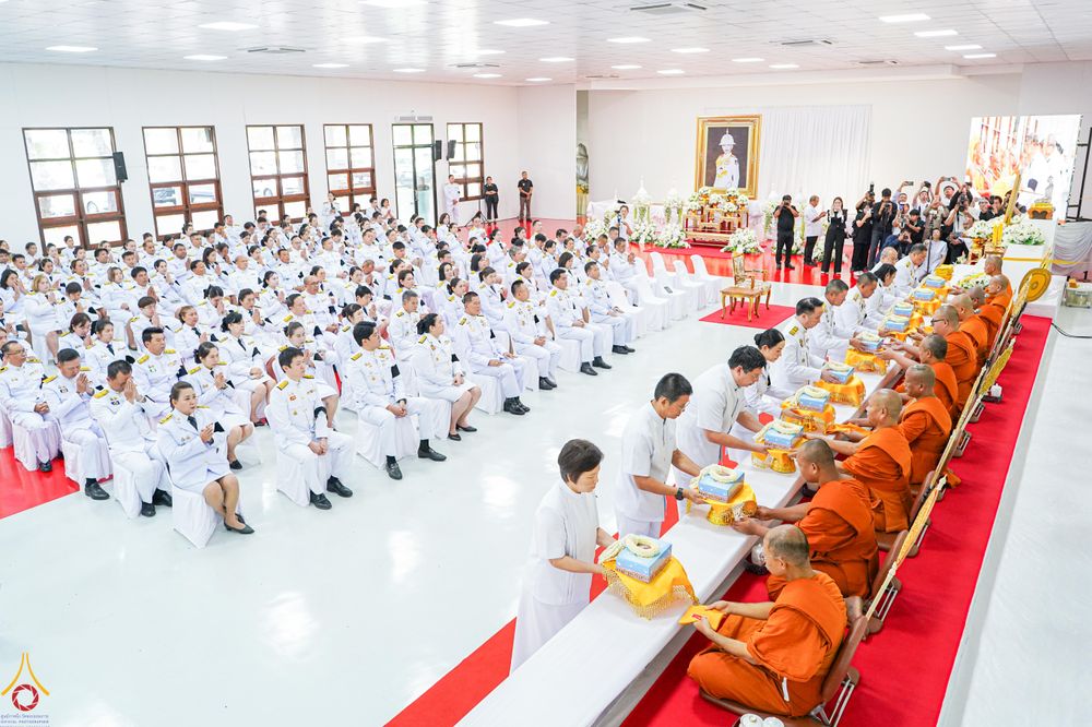 พุทธศาสนิกชนแต่งกายชุดสีขาวร่วมพิธีบำเพ็ญกุศลและถวายจตุปัจจัยไทยธรรมแด่พระสงฆ์ภายในอาคาร