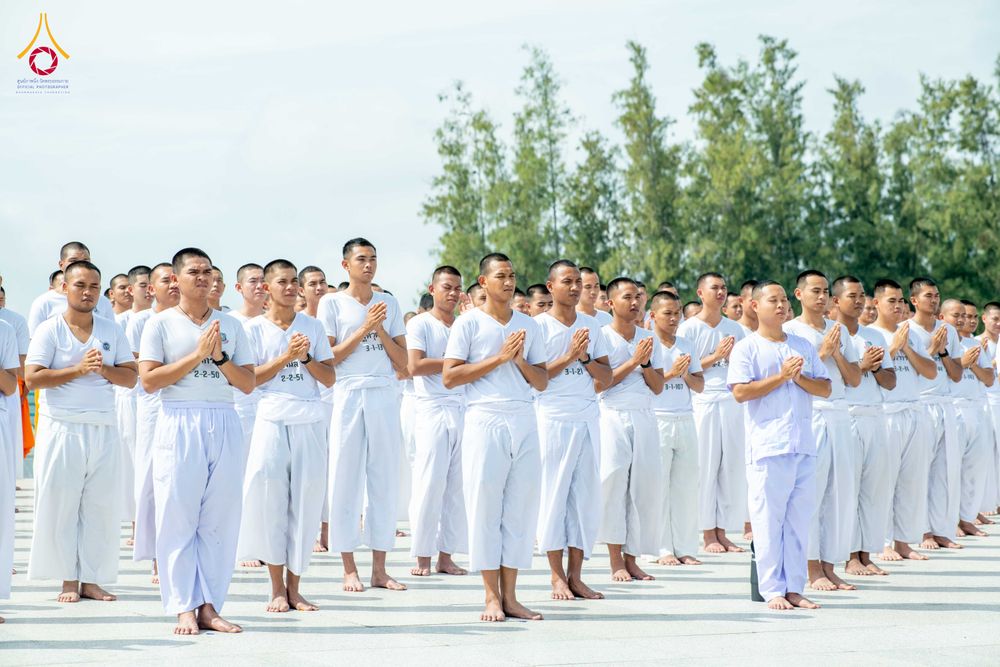 กลุ่มนักเรียนนายสิบตำรวจสวมชุดขาวปฏิบัติธรรมยืนพนมมือเรียงแถวอย่างเป็นระเบียบ
