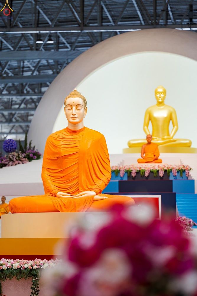 พระพุทธรูปองค์ใหญ่สีทองห่มจีวรสีส้มประดิษฐานอยู่ด้านหน้าและมีพระพุทธรูปองค์สีทองอยู่ด้านหลัง