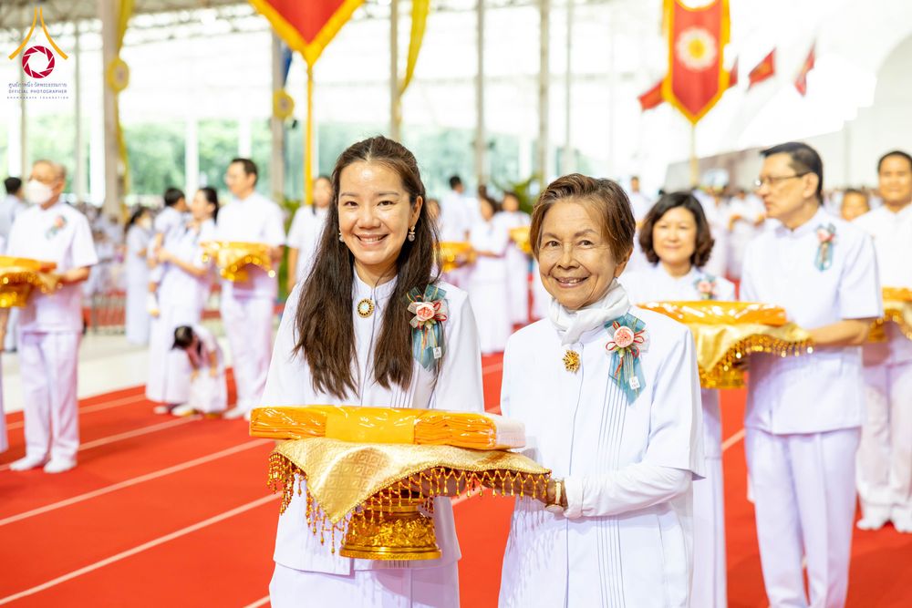 กลุ่มพุทธศาสนิกชนสวมชุดขาวถือพานผ้าไตรจีวรสีเหลืองทองในพิธีทอดผ้าป่า