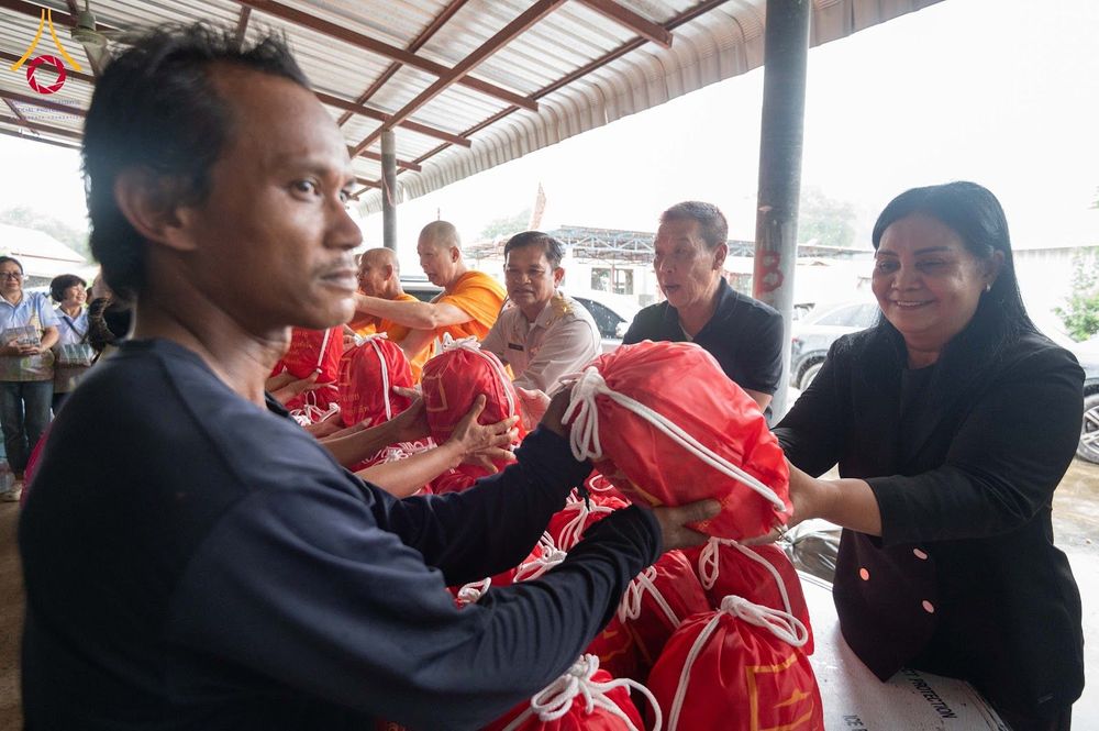 กลุ่มคนและพระภิกษุสงฆ์กำลังส่งมอบถุงยังชีพสีแดงให้แก่ประชาชนในพื้นที่ประสบภัย
