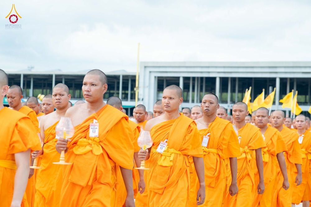 กลุ่มพระภิกษุสงฆ์ห่มจีวรสีส้มเดินแถวถือโคมเทียนแก้วใสในพิธีกรรมทางศาสนา
