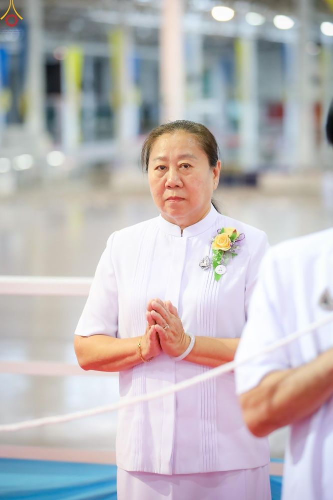หญิงวัยกลางคนสวมชุดสีขาวพนมมือในท่าทางสำรวม
