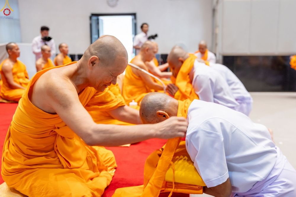 พระภิกษุสงฆ์กำลังมอบผ้าไตรจีวรให้แก่ผู้ที่กำลังจะบรรพชาอุปสมบทในพิธีทางศาสนา