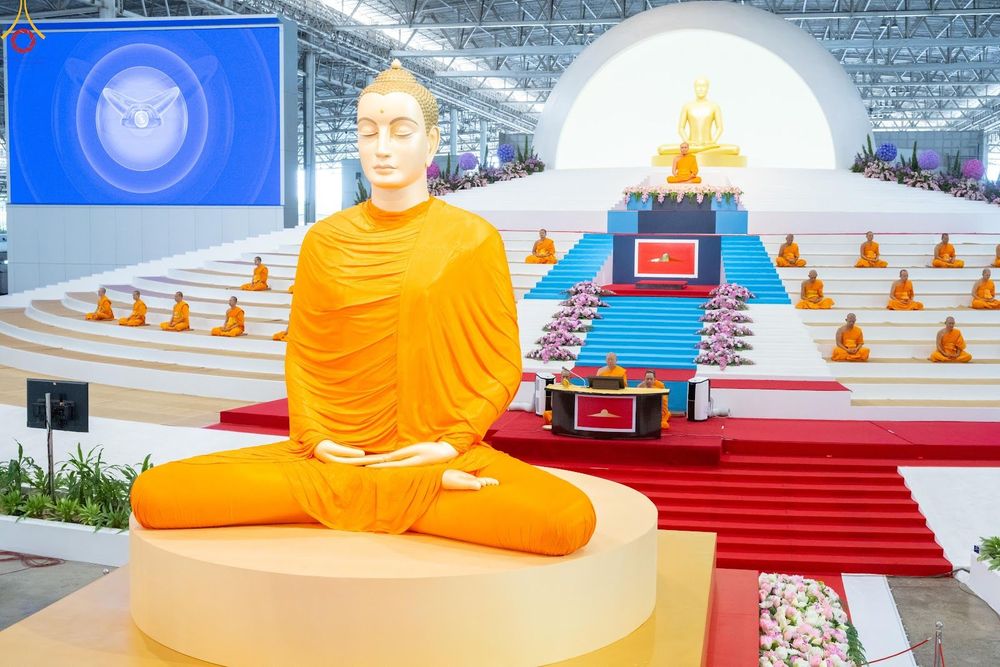 พระพุทธรูปองค์ใหญ่และพระภิกษุสงฆ์นั่งสมาธิบนอัฒจันทร์ในพิธีทางศาสนา