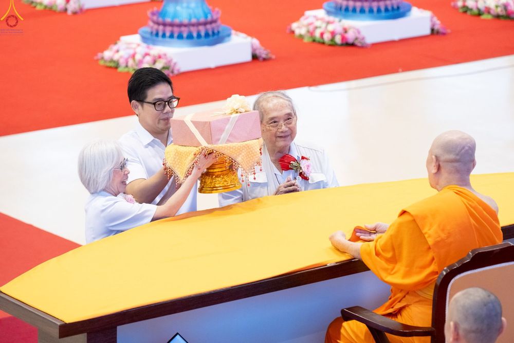 กลุ่มคนกำลังประคองพานพุ่มผ้าป่าเพื่อถวายแด่พระภิกษุสงฆ์ในพิธีทางศาสนา