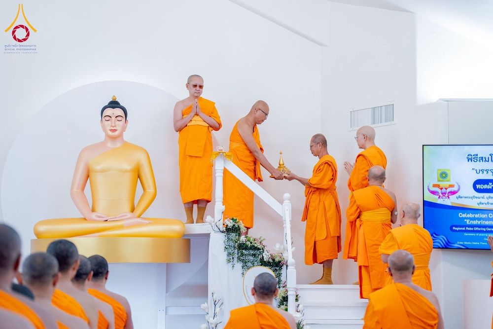 พระภิกษุสงฆ์ในจีวรสีส้มกำลังประกอบพิธีทางศาสนาหน้าพระพุทธรูปองค์สีทองภายในวัด