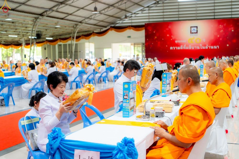 พุทธศาสนิกชนกำลังถวายสังฆทานแด่พระภิกษุสงฆ์ภายในงานบุญที่มีผู้คนเข้าร่วมจำนวนมาก