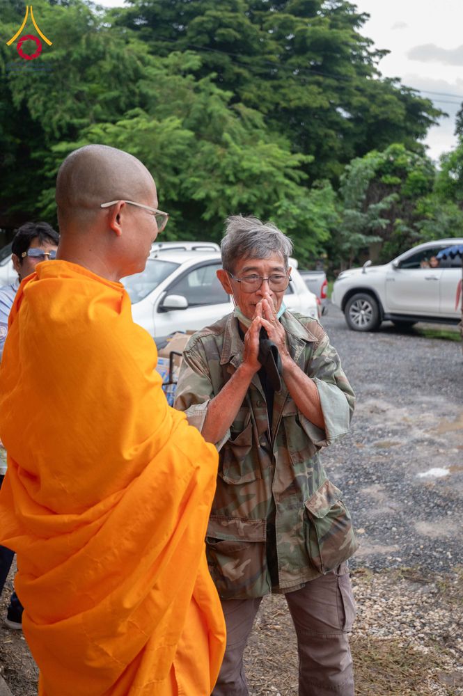 พระสงฆ์กำลังสนทนากับชายสูงวัยที่กำลังยกมือไหว้ในพื้นที่กลางแจ้ง
