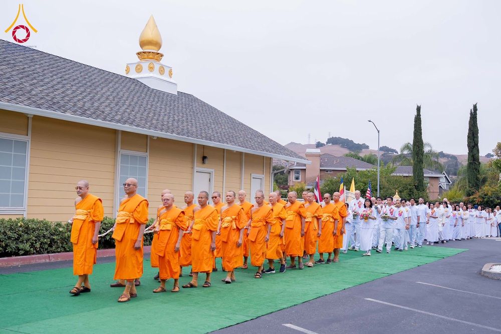 ขบวนพระภิกษุสงฆ์และพุทธศาสนิกชนเดินแถวประกอบพิธีทางศาสนาบริเวณหน้าอาคาร