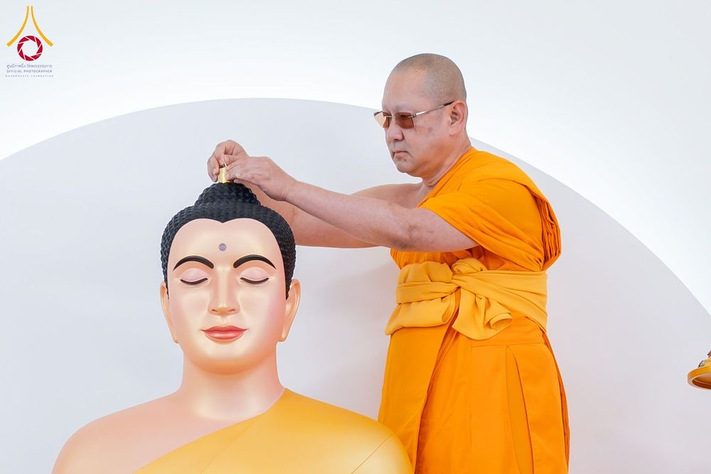 พระภิกษุสงฆ์กำลังอัญเชิญพระบรมสารีริกธาตุประดิษฐานบนพระเศียรพระพุทธรูป
