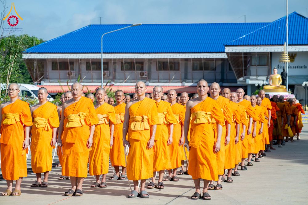 พระภิกษุสงฆ์จำนวนมากในจีวรสีเหลืองเดินเรียงแถวในพิธีทางศาสนาหน้าอาคาร