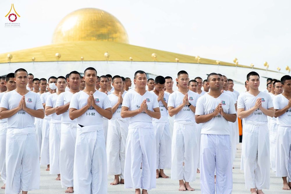 กลุ่มนักเรียนนายสิบตำรวจสวมชุดขาวพนมมือปฏิบัติธรรมกลางแจ้ง