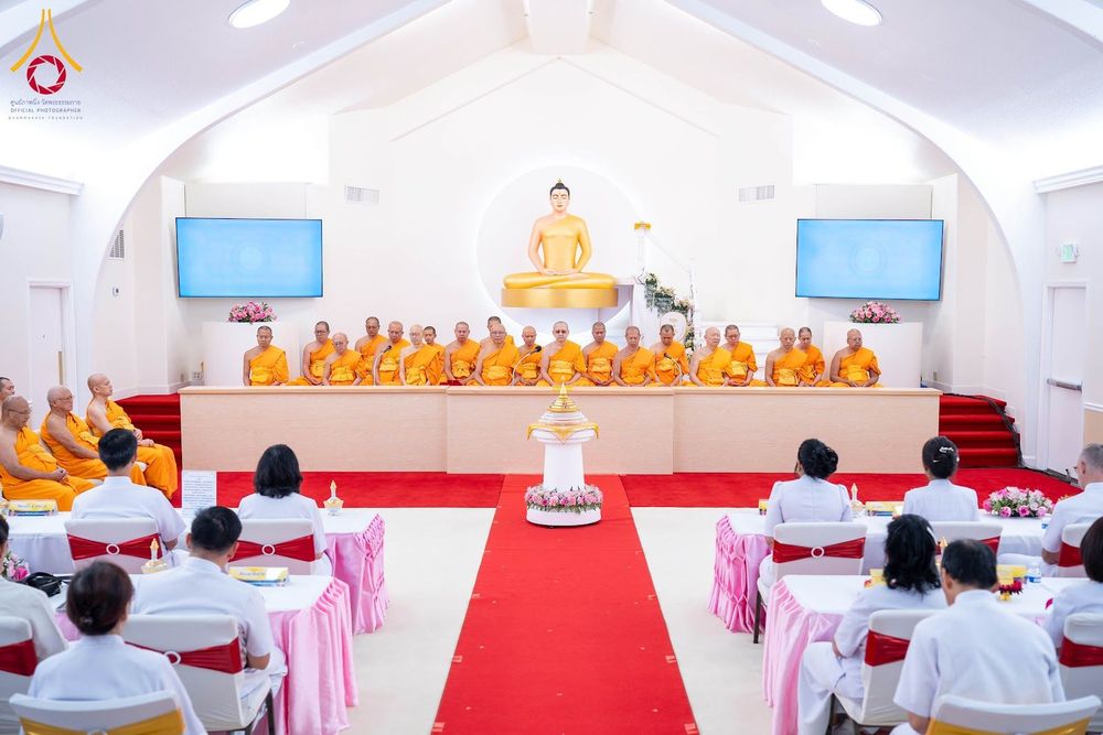 คณะสงฆ์และพุทธศาสนิกชนร่วมพิธีทางศาสนาภายในอาคารที่มีพระพุทธรูปประดิษฐานอยู่ด้านหน้า