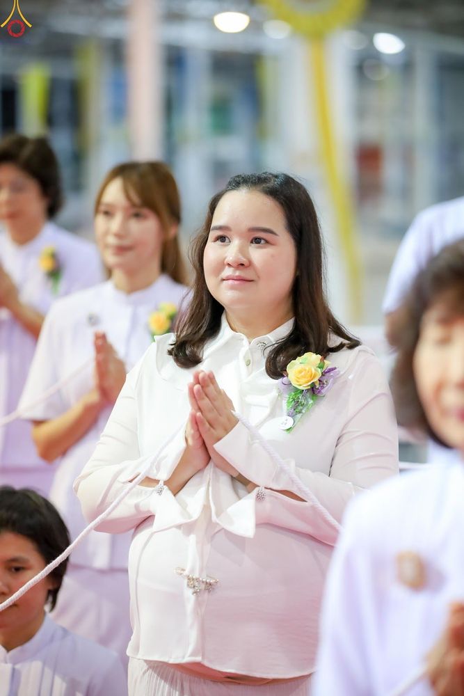 หญิงสาวสวมชุดสีขาวพนมมือด้วยความสงบในพิธีทางศาสนา