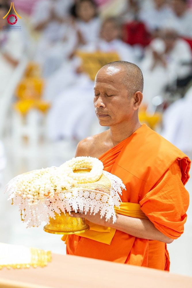 พระภิกษุสงฆ์ถือพานพวงมาลัยดอกมะลิสีขาวด้วยท่าทางสำรวม