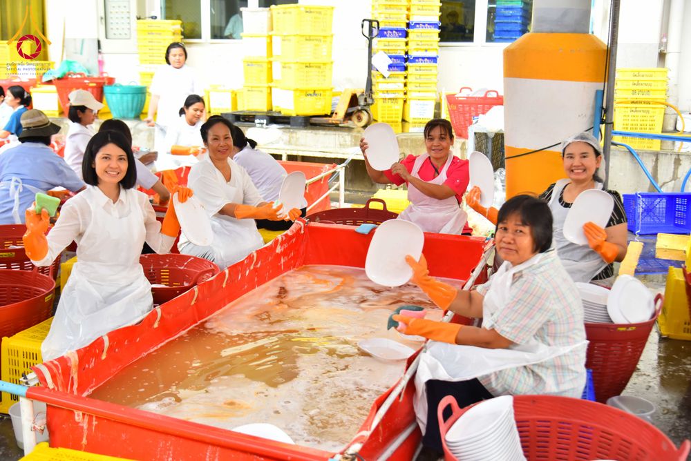 อาสาสมัครหลายคนกำลังช่วยกันล้างจานในอ่างน้ำขนาดใหญ่ภายในโรงครัว