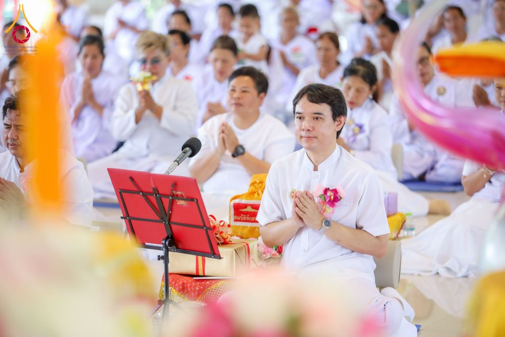 กลุ่มคนสวมชุดสีขาวนั่งพนมมือร่วมกิจกรรมอบรมทางศาสนาภายในอาคาร