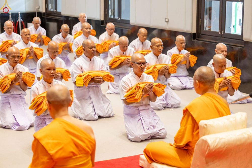 ผู้เข้าร่วมโครงการอุปสมบทหมู่ในชุดสีขาวนั่งพนมมือถือผ้าไตรจีวรเตรียมเข้าพิธีบรรพชา