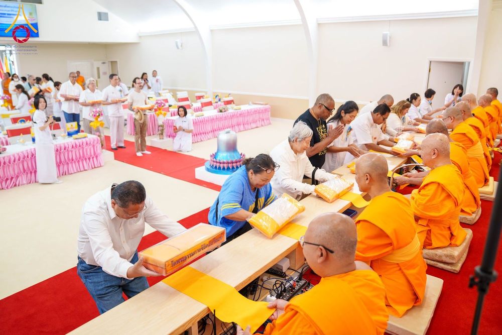 พุทธศาสนิกชนกำลังถวายผ้าไตรแด่พระภิกษุสงฆ์ในพิธีทอดผ้าป่า